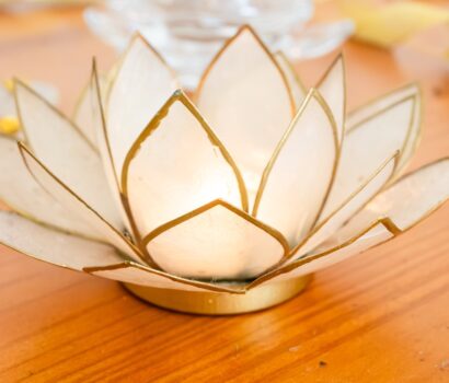 imagen de un sujeta velas en forma de flor de loto blanco con los bordes dorados.