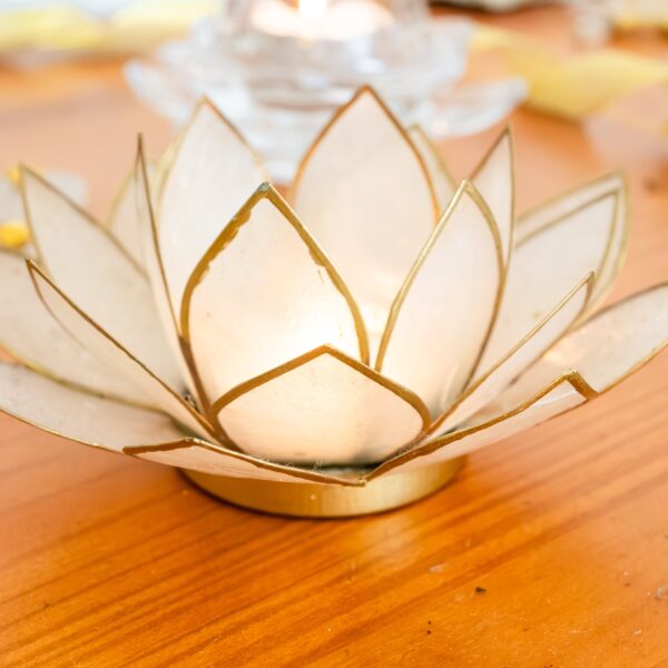 imagen de un sujeta velas en forma de flor de loto blanco con los bordes dorados.