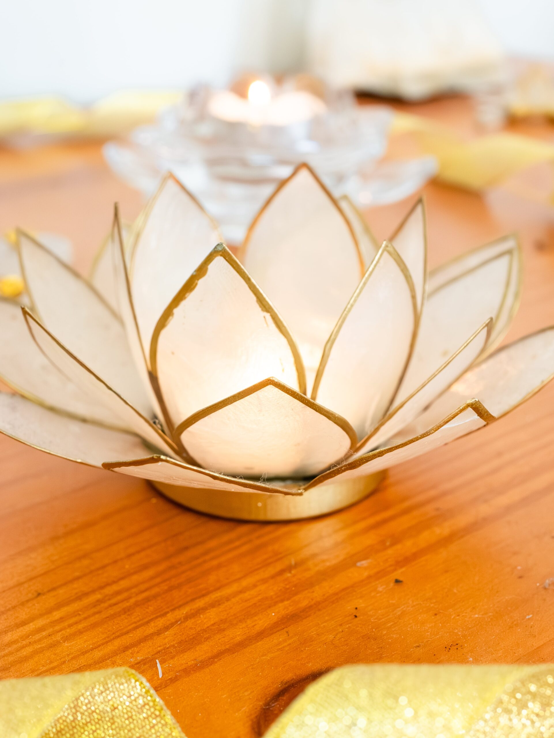 imagen de un sujeta velas en forma de flor de loto blanco con los bordes dorados.