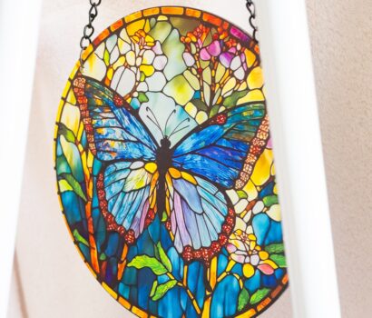 Foto detalle de un elemento decorativo de una mariposa con muchos colores en tonos verdes y azules que tiene Carmen en su local como decoración