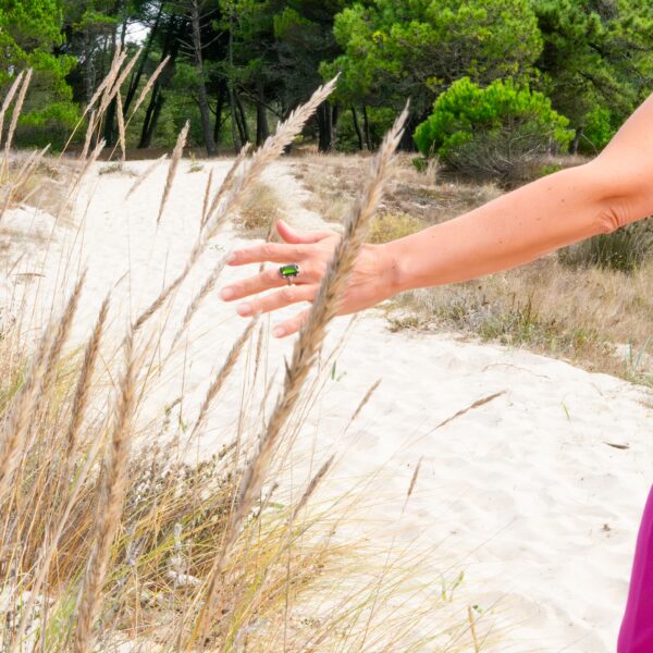 Carmen tocando las hierbas de los arenales por la playa