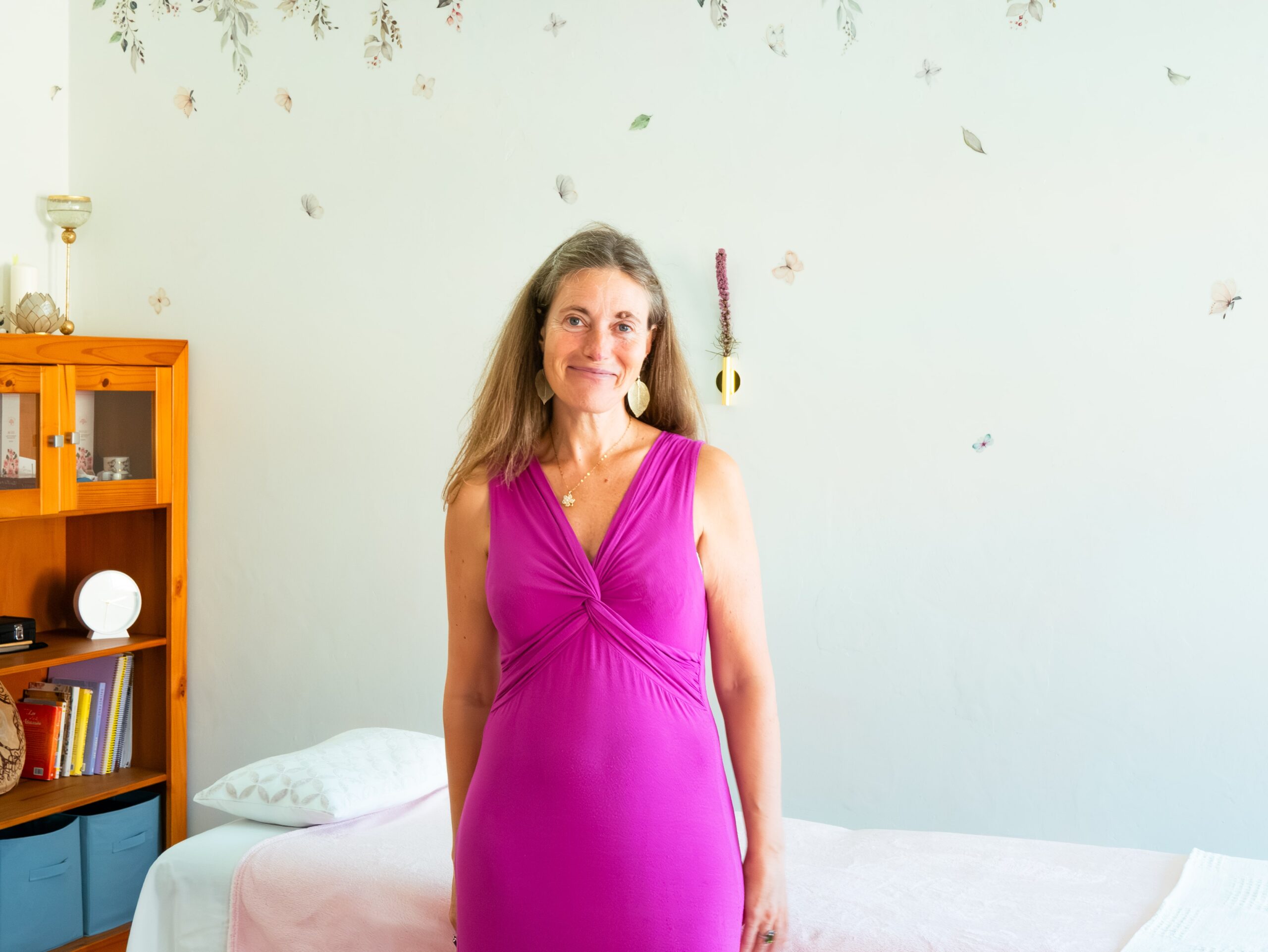 Carmen C. Malvar delante de la camilla de su local en O Hío con un vestido rosa, sonriendo